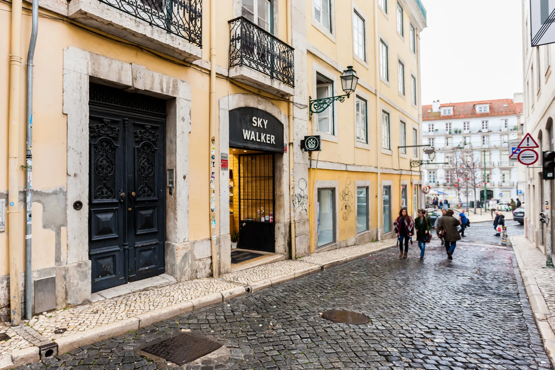 Una calle empedrada bordeada de edificios pastel y peatones.