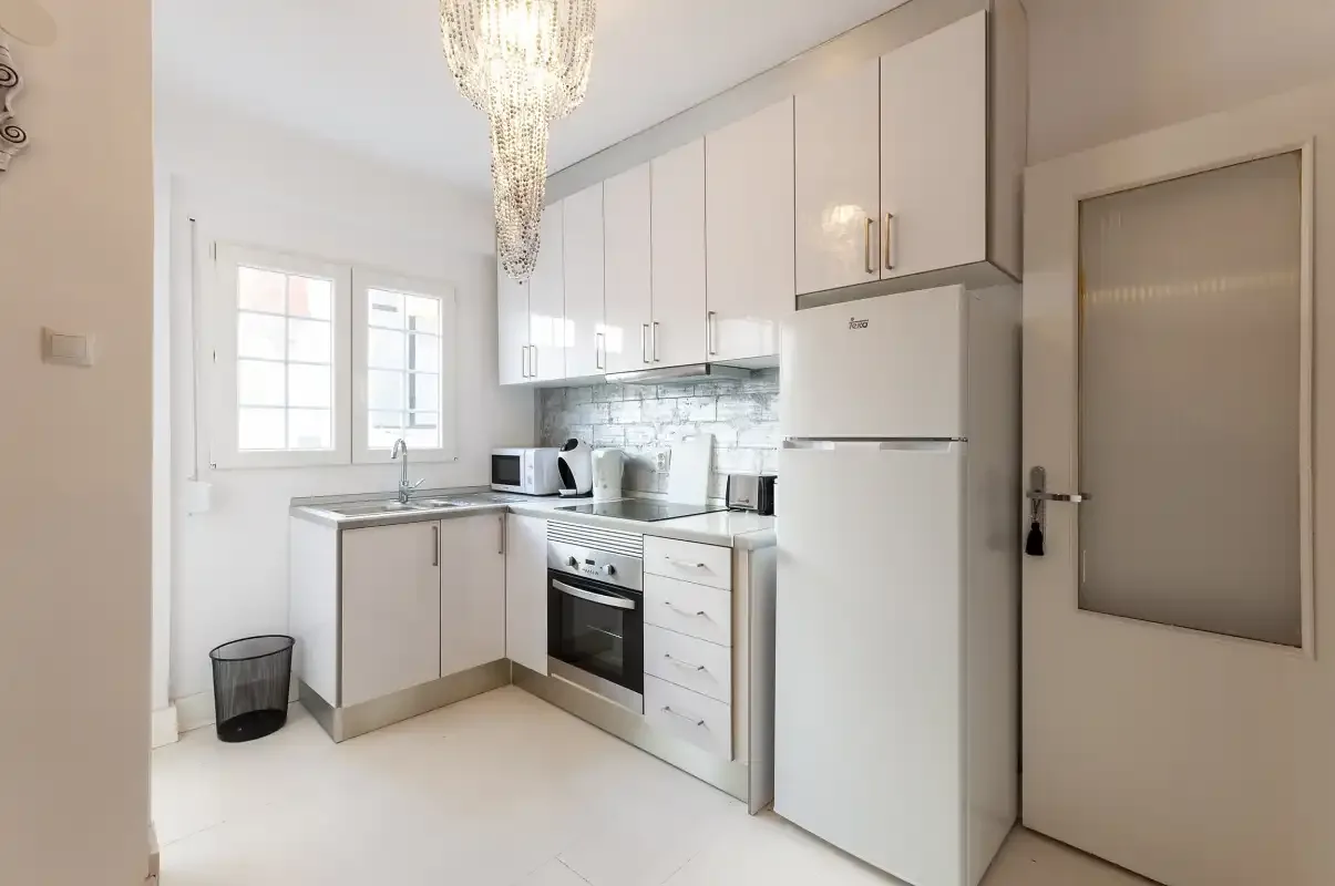 A bright kitchen with white cabinets, appliances, and a window.