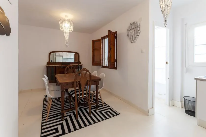 A dining area with a wooden table and chairs on a striped rug.