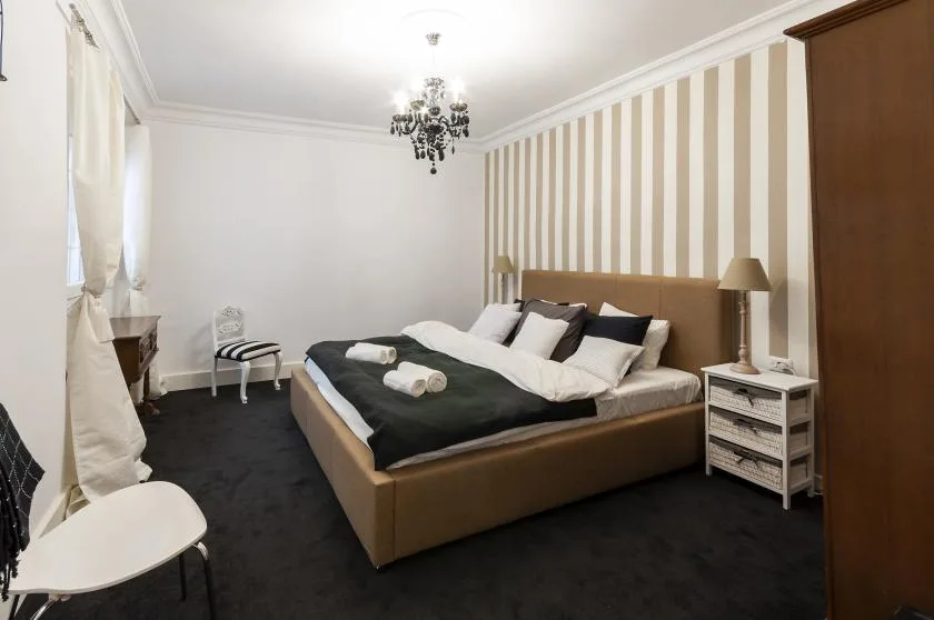 A bedroom with a large bed, striped accent wall, and bedside tables.