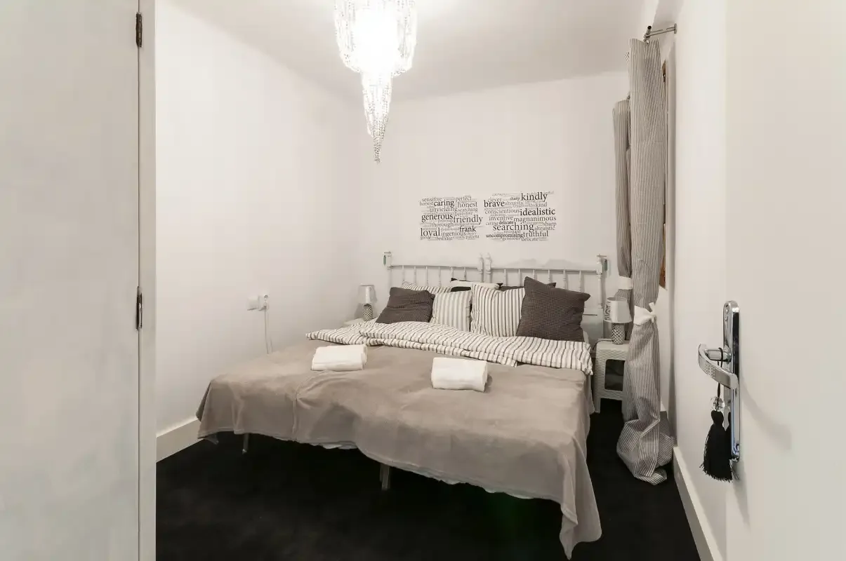 A bedroom with a bed dressed in neutral bedding and pillows.
