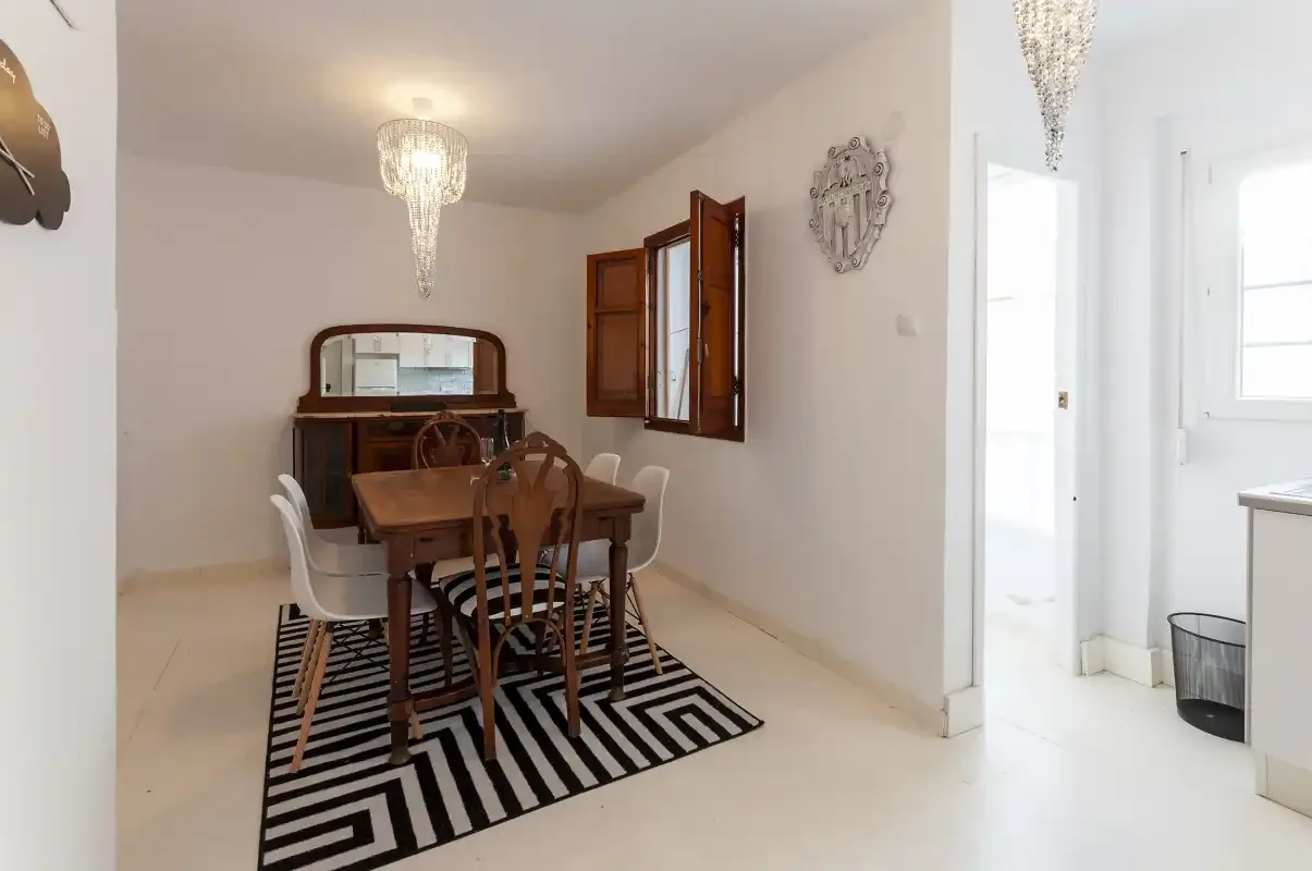 A dining room with a wooden table and chairs over a striped rug.