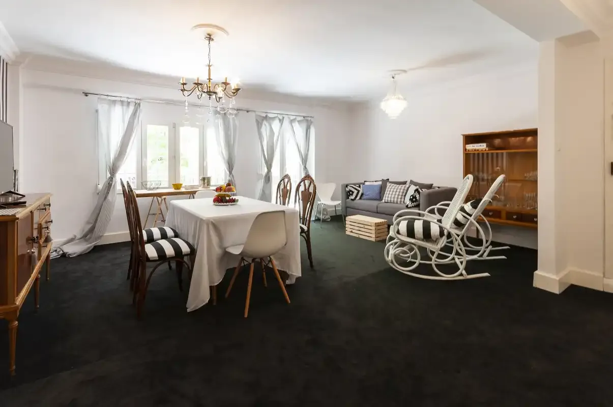 A dining and living room with a table, seating, and a rocking chair.