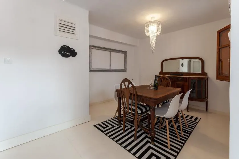 A dining area with a wooden table and chairs on a striped rug.