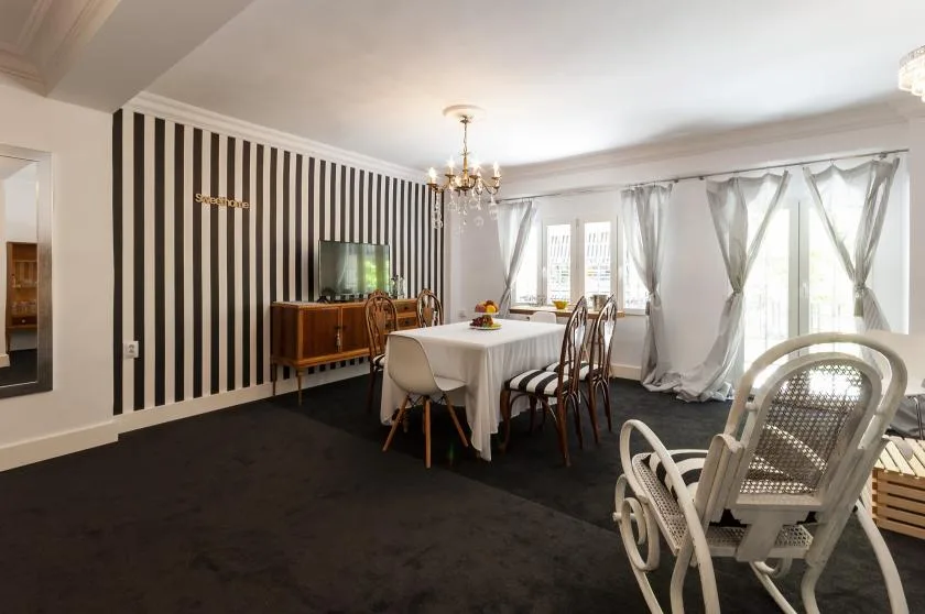 A dining room with a table, striped accent wall, and large windows.