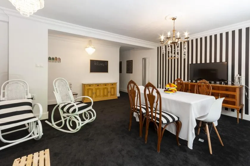 A dining area with a table, chairs, and a television against a striped wall.