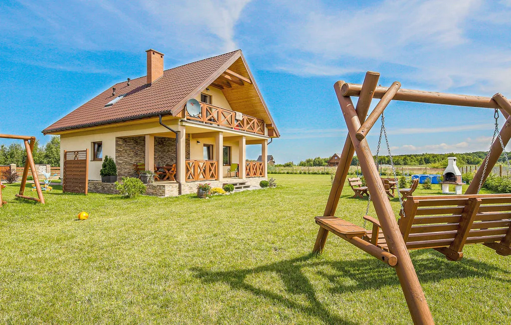 Una casa de campo con un columpio de madera en un amplio jardín de césped.