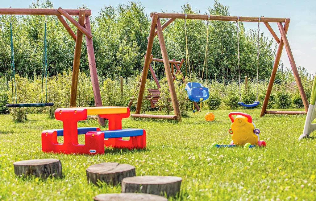 A grassy outdoor playground with swings, a slide, and colorful play equipment.