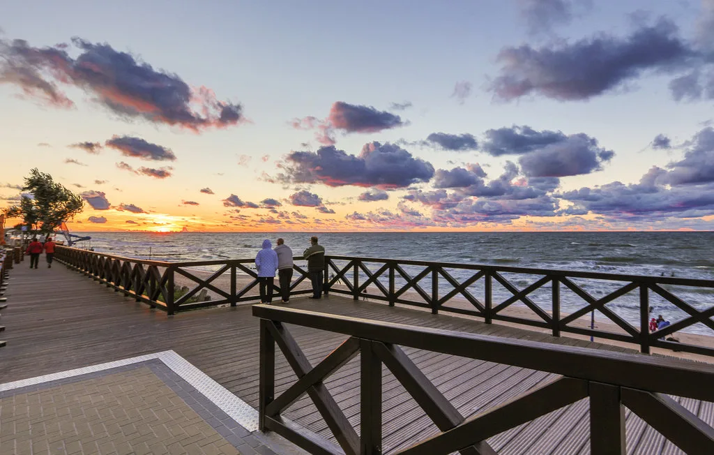 A wooden boardwalk overlooks the ocean beneath a colorful sunset sky.
