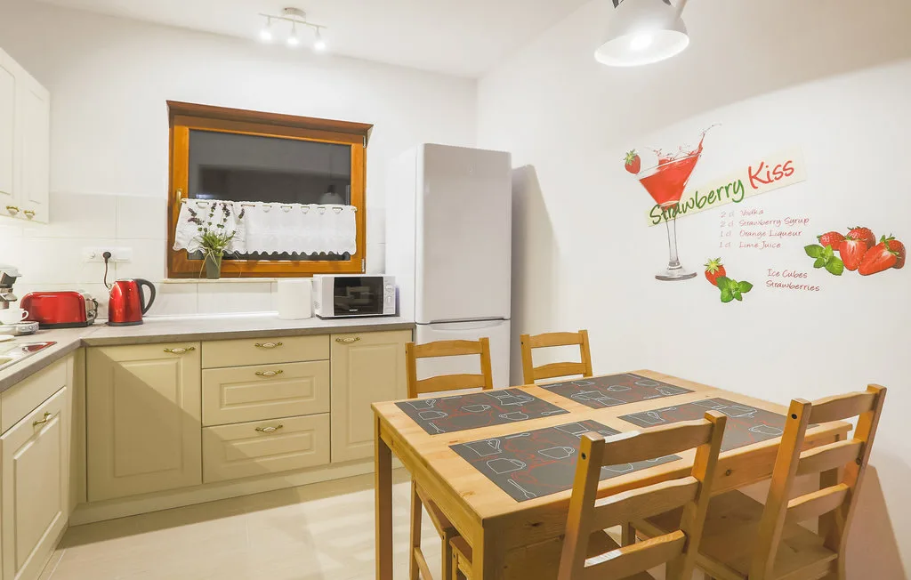 A kitchen and dining area with a wooden table and colorful wall decoration.