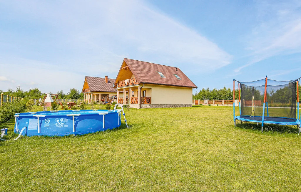 A house stands in a grassy yard with an above-ground pool and trampoline.