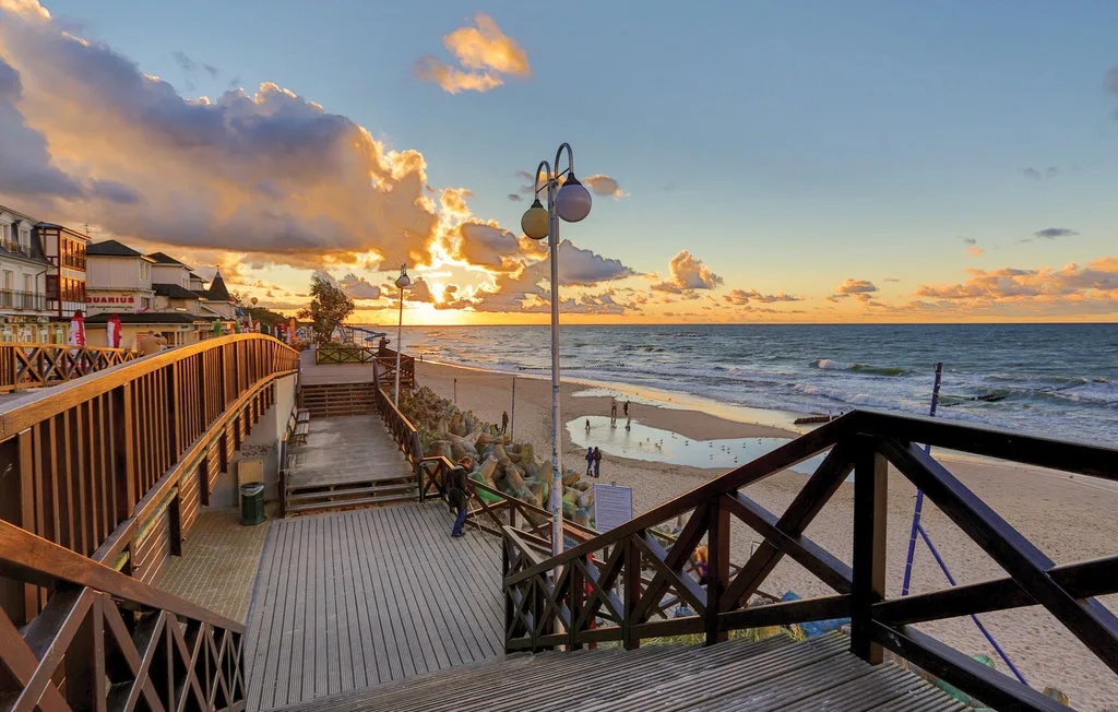 A beach boardwalk overlooks the ocean beneath a colorful sunset sky.