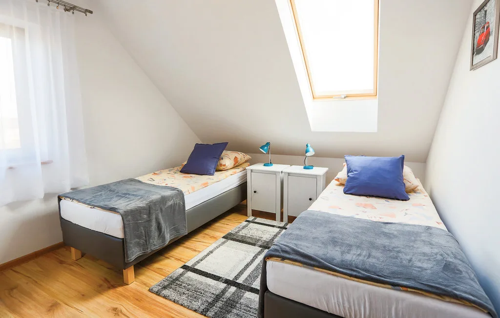 A bright attic bedroom has two single beds and a skylight.