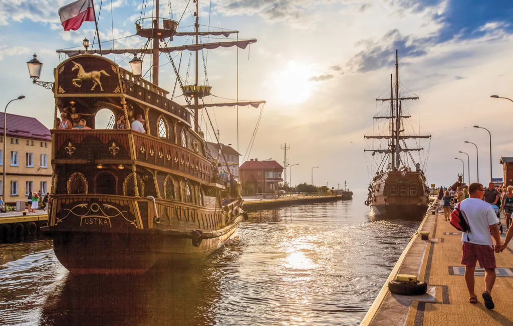 A harbor scene with decorated sailing ships moored along the waterfront.
