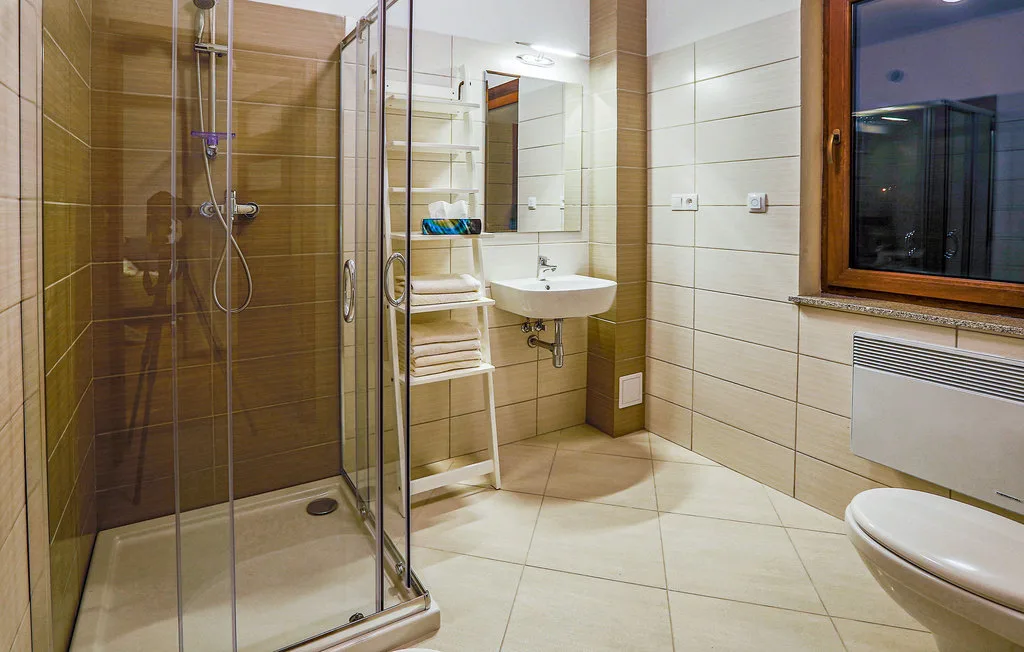 A tiled bathroom with a glass shower, sink, and mirror.
