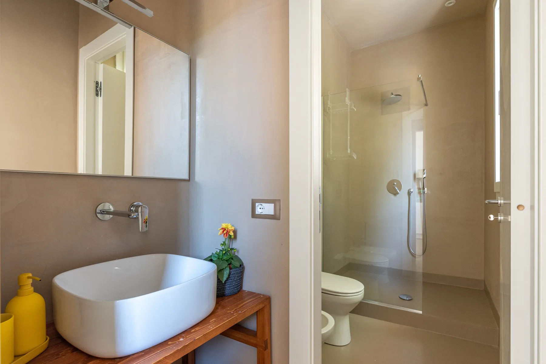 Un baño con un lavabo sobre encimera y una ducha acristalada.