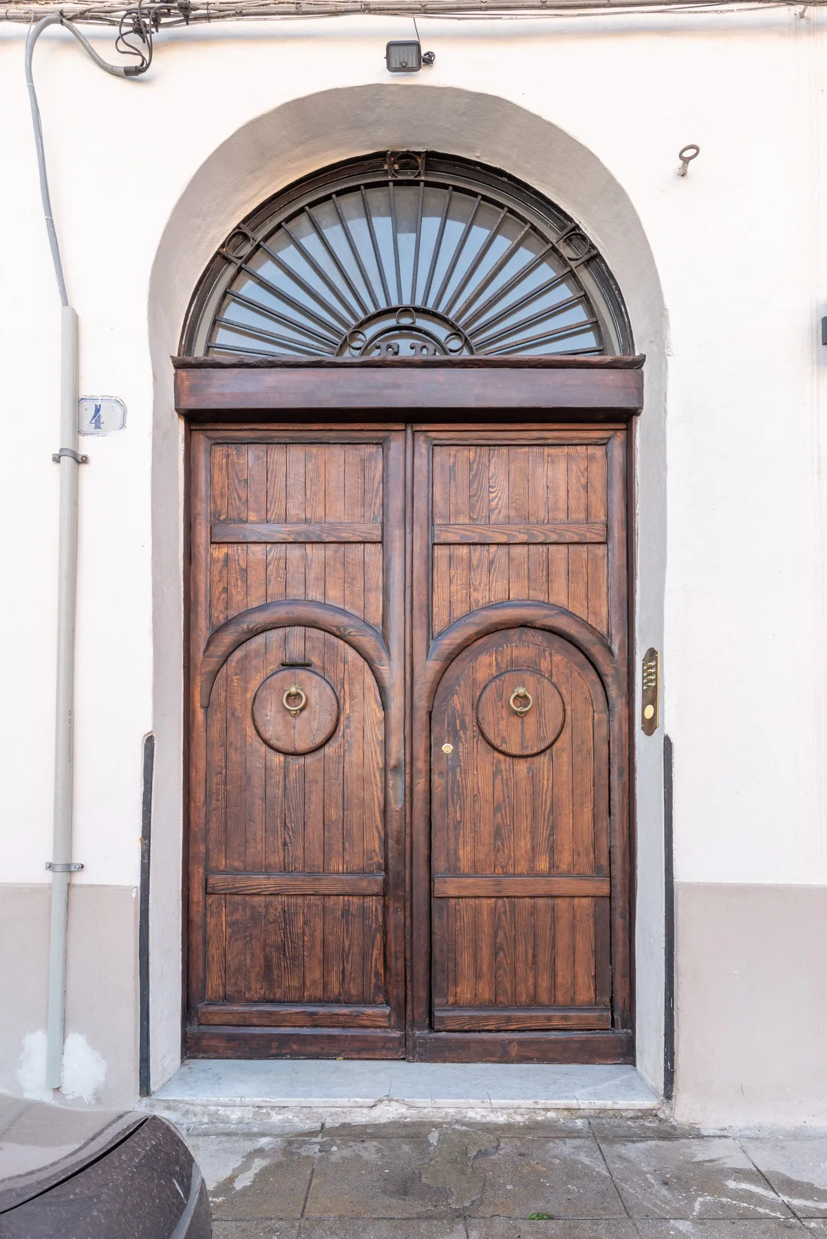 Una puerta de entrada de madera con arco y una ventana semicircular encima.
