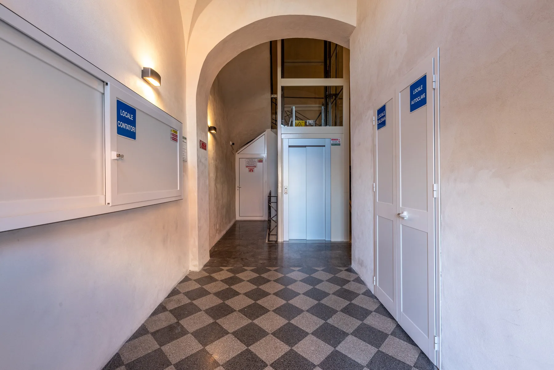 Un pasillo interior con arco, suelo de baldosas estampadas y varias puertas.