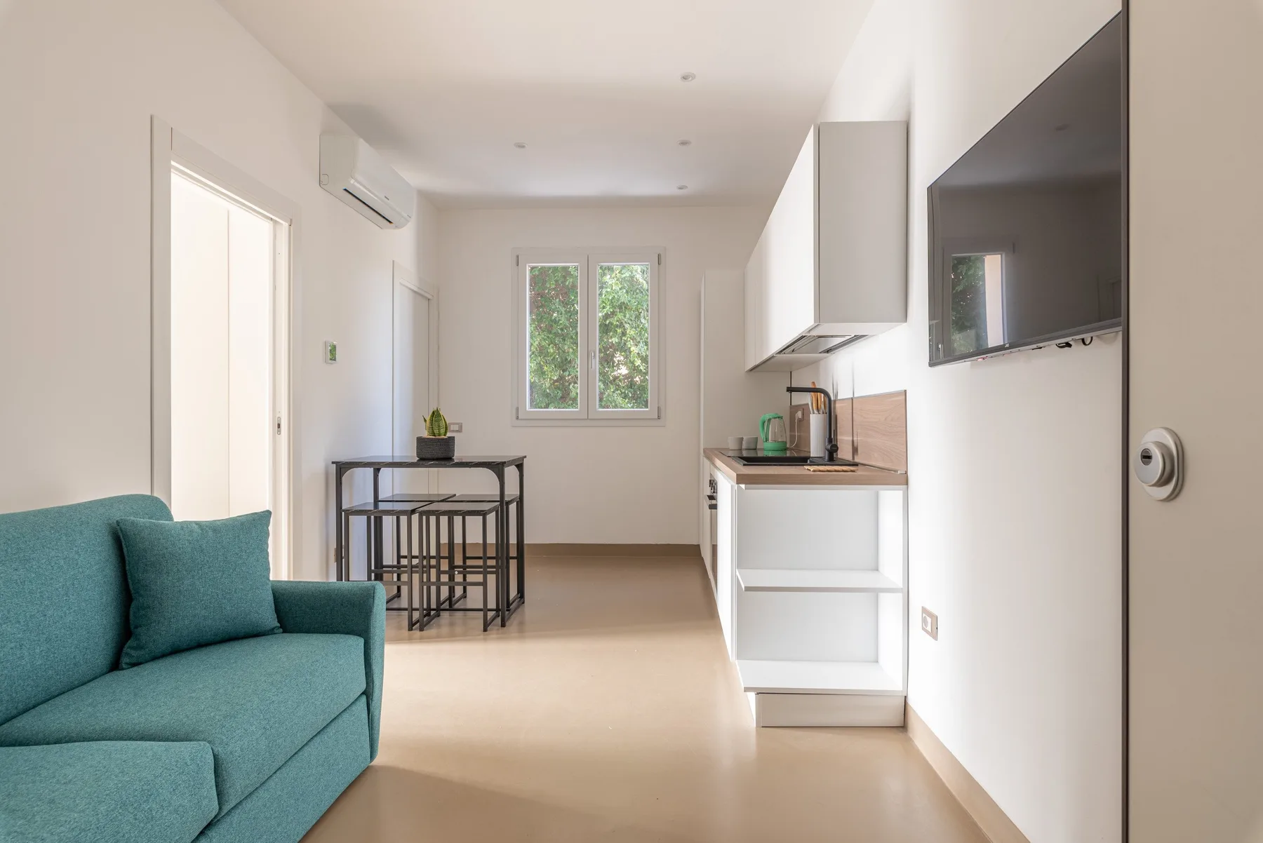 Una estancia diáfana y luminosa con cocina pequeña, mesa de comedor y asientos.