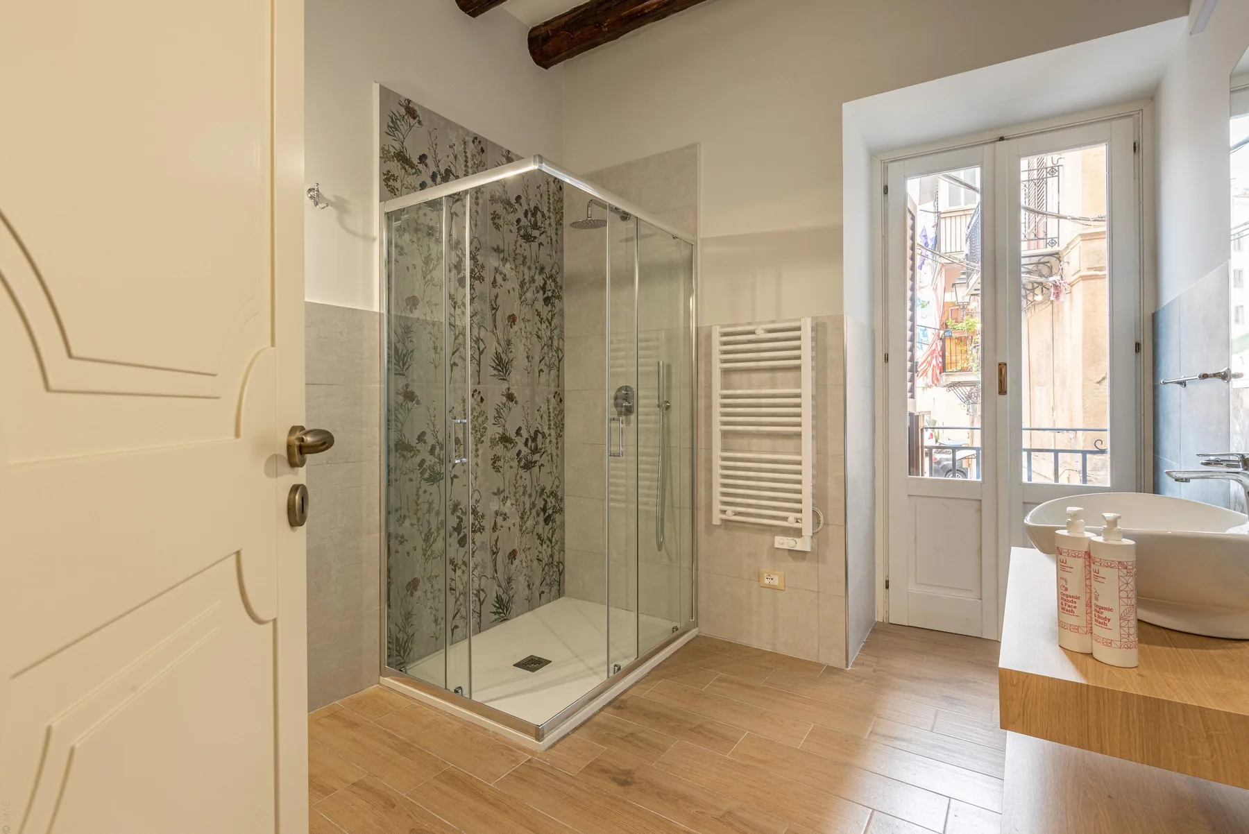 A bright bathroom with a glass shower, towel warmer, and sink.
