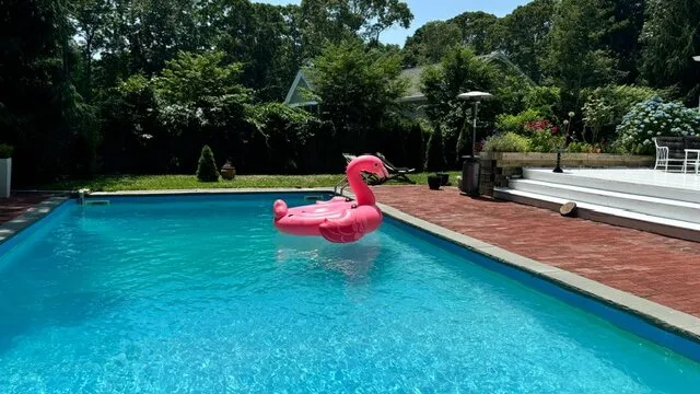 Una piscina al aire libre con un flamenco inflable rosa flotando en el agua.