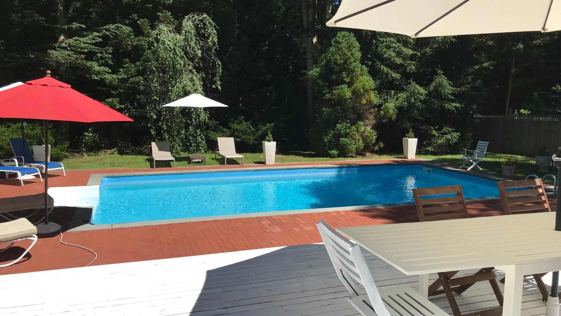 Una piscina al aire libre con asientos de patio y sombrillas.