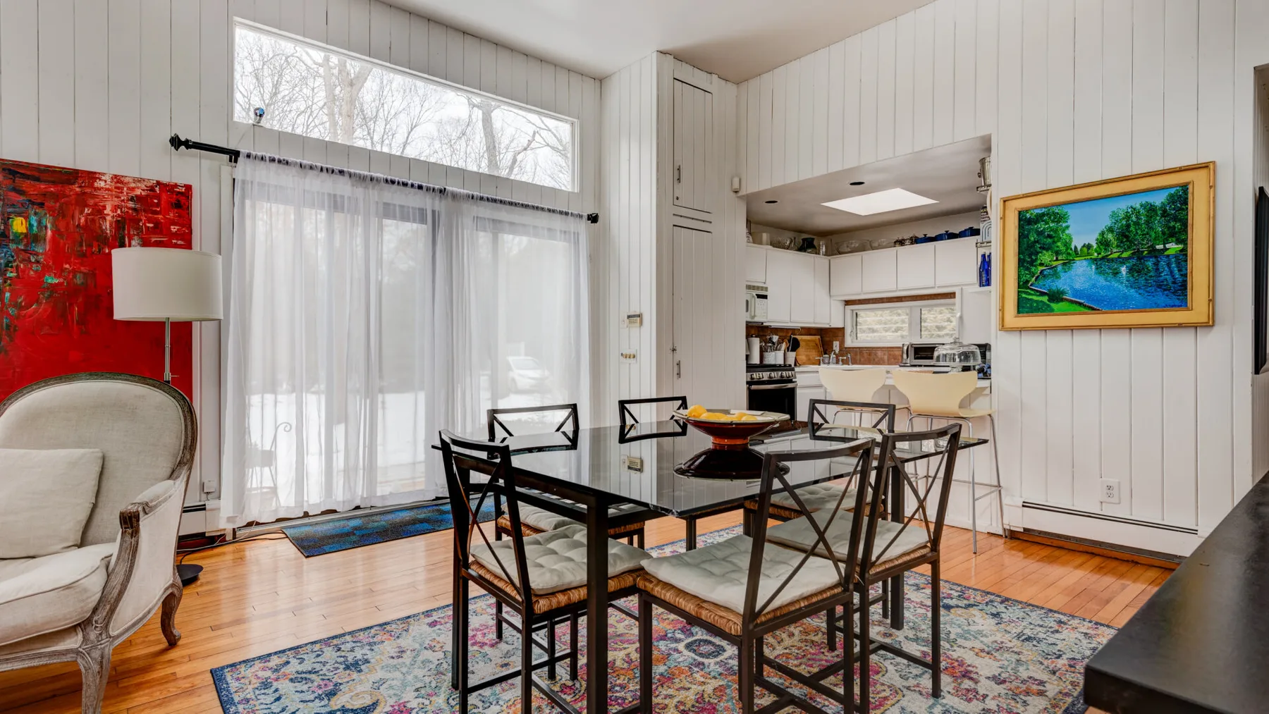 Un comedor con una mesa oscura y sillas está junto a una cocina luminosa.