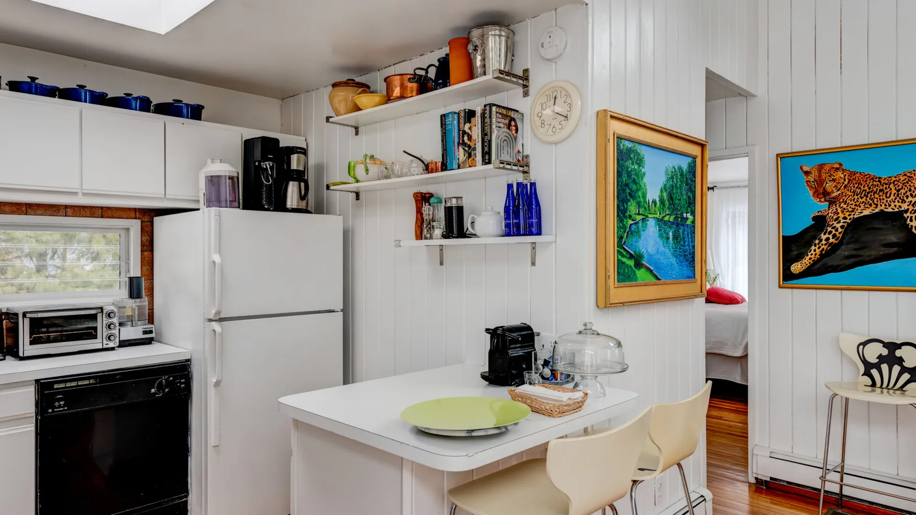 Una cocina compacta con gabinetes blancos, un refrigerador y una pequeña barra para comer.