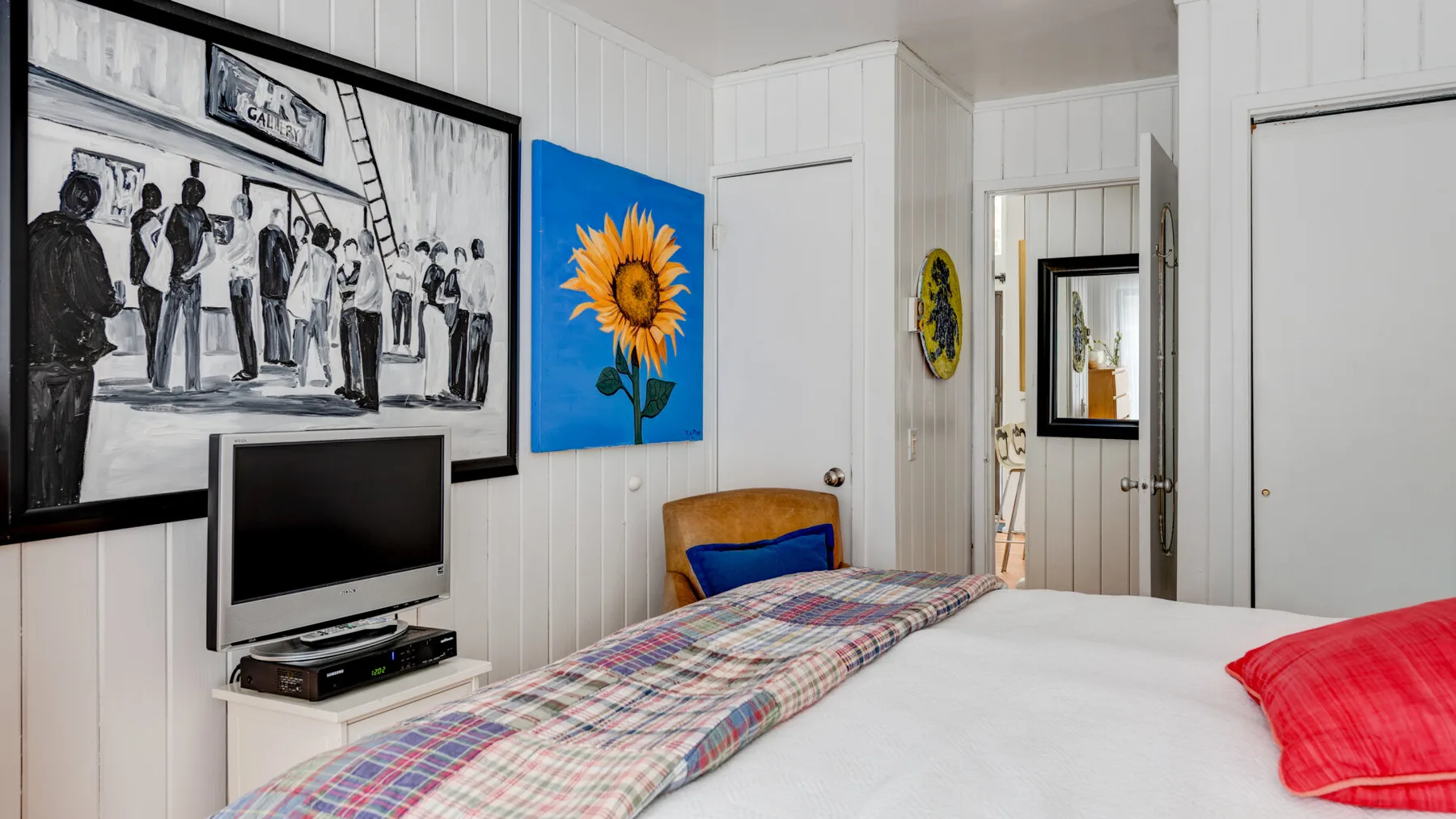 Un dormitorio con una cama grande, ropa de cama colorida y cuadros en la pared.