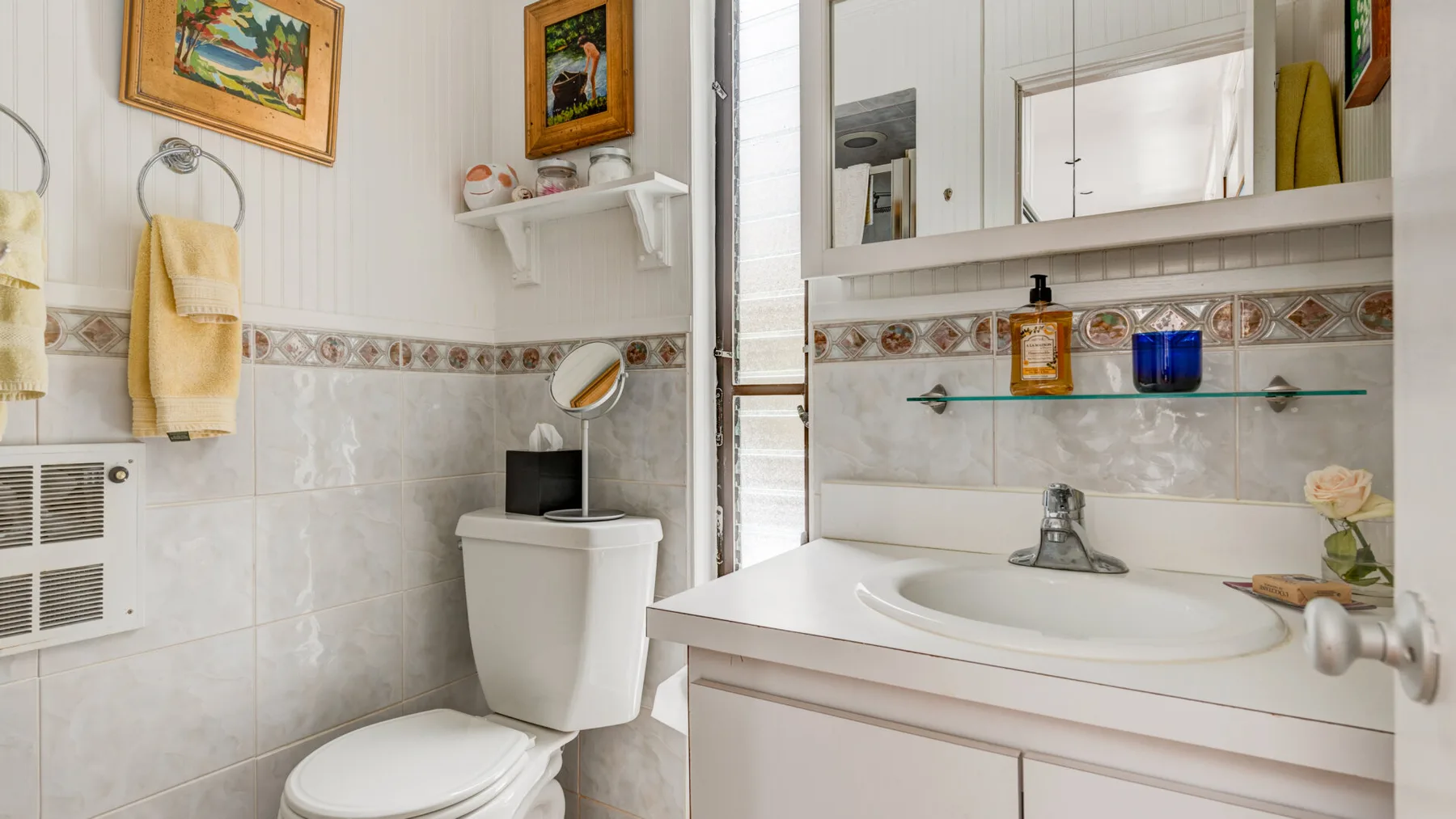 Un baño con lavabo, espejo e inodoro.