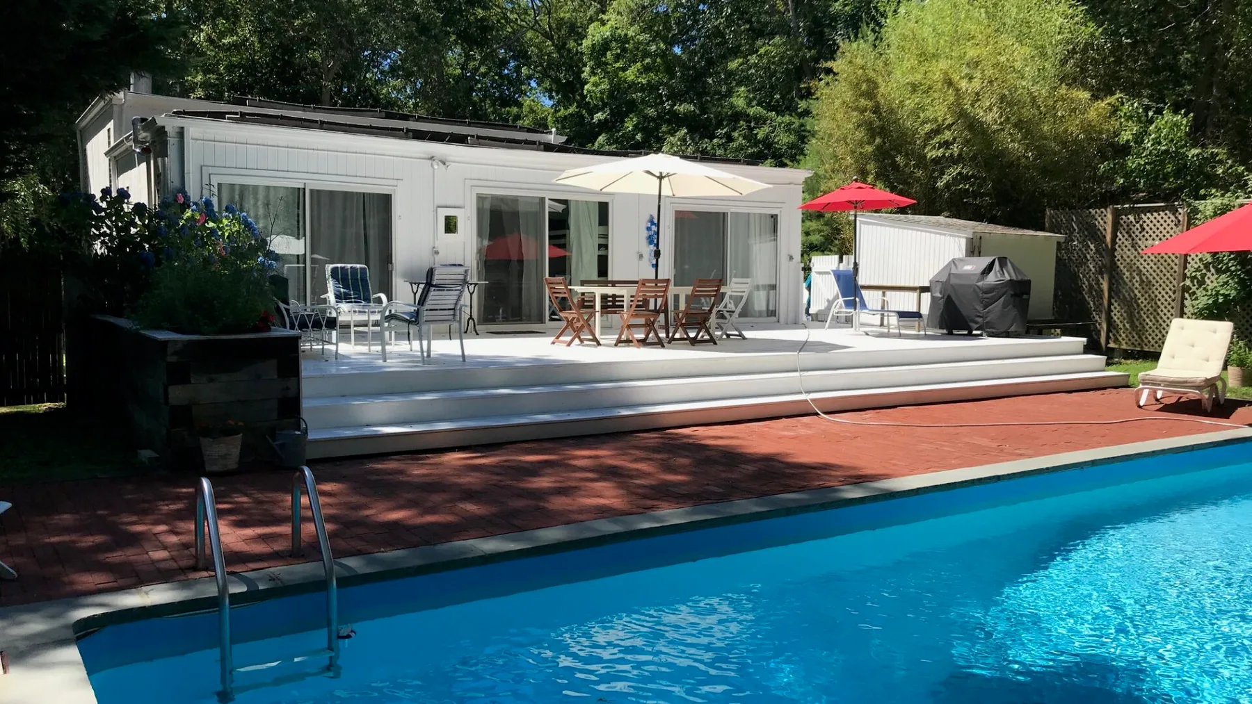 Una piscina al aire libre está junto a una casa moderna con una zona de asientos en el patio.