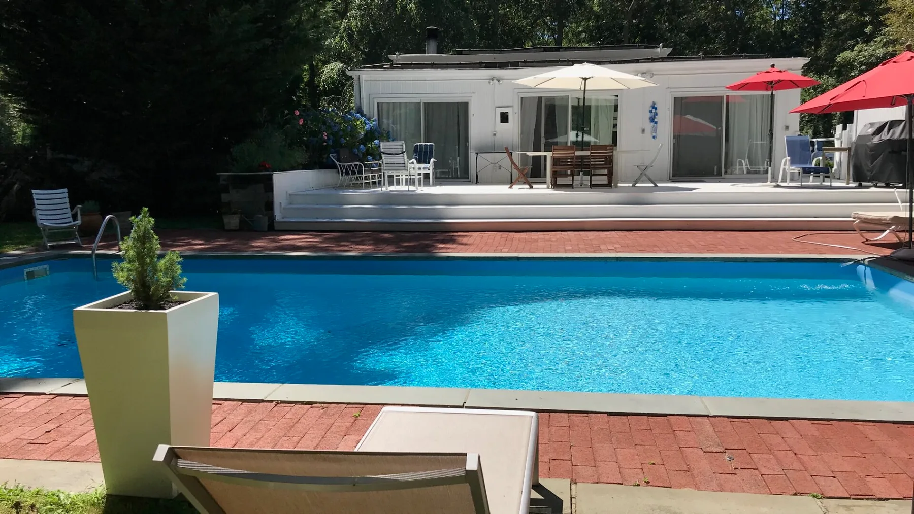 Una piscina al aire libre con tumbonas y un patio al fondo.