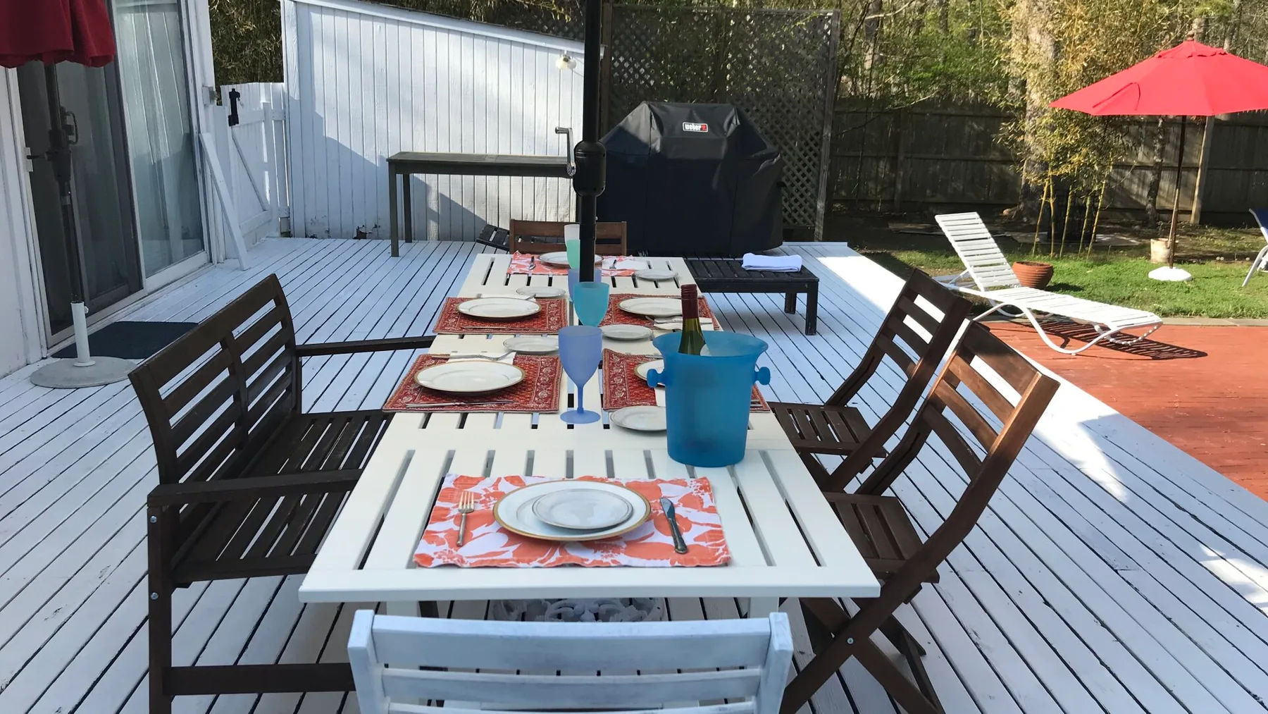 Una zona de comedor en la terraza con la mesa puesta y una parrilla cerca.