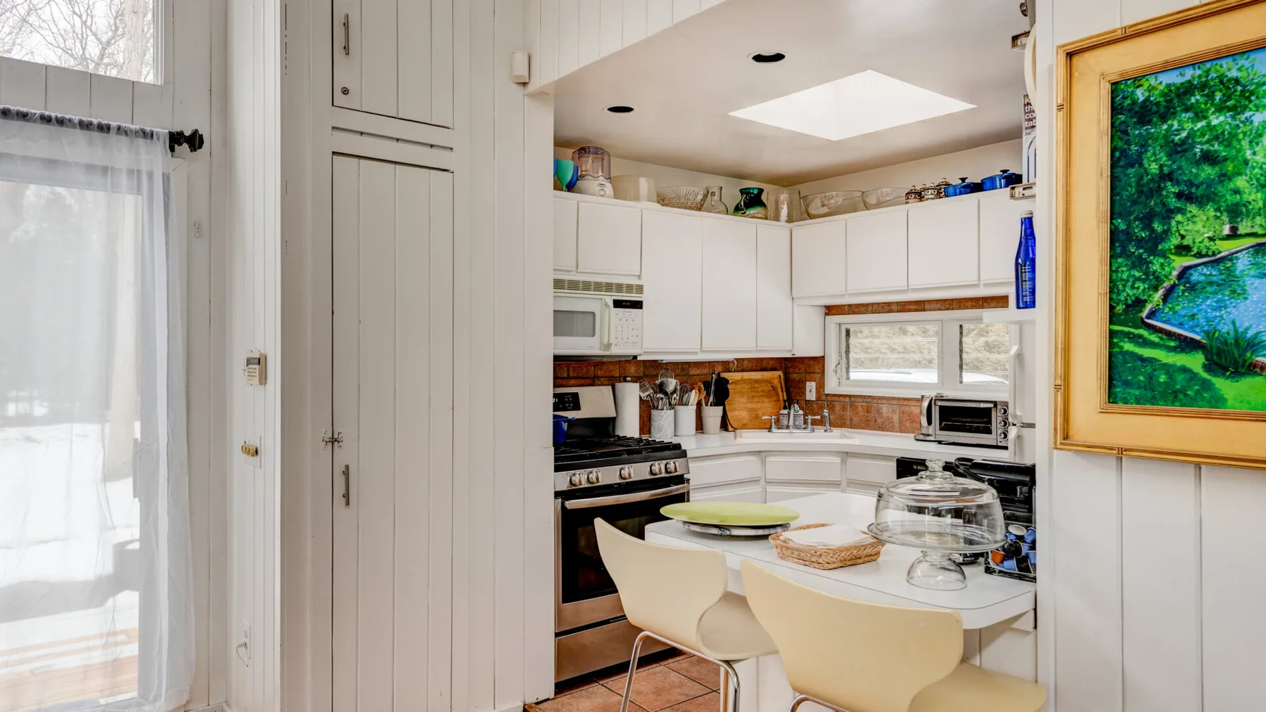 Una cocina luminosa con gabinetes blancos y una mesa de comedor.