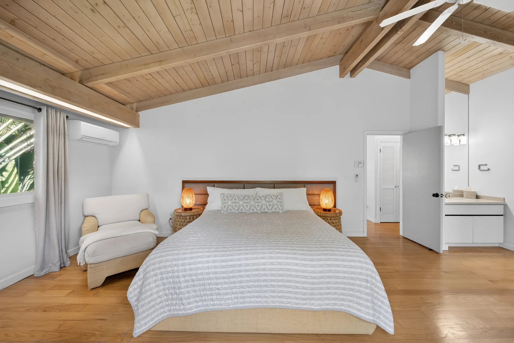 Un dormitorio con una cama grande, lámparas de noche y un techo inclinado de madera.