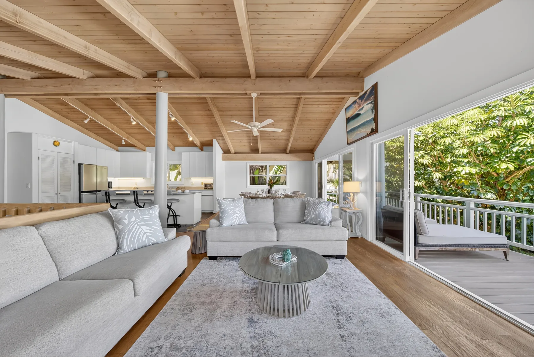A bright living room with seating, a coffee table, and an open view to the deck.