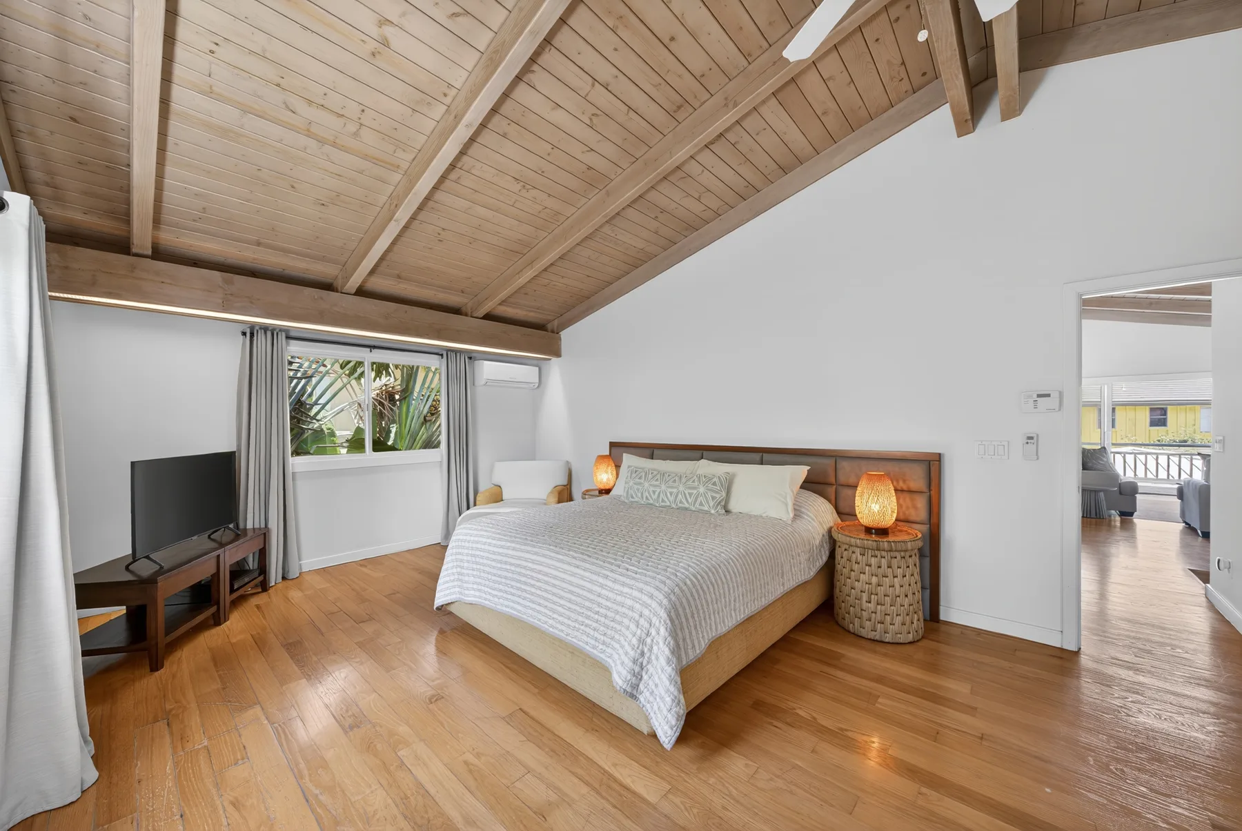 Un dormitorio con una cama, mesas de noche y un techo de madera inclinado.