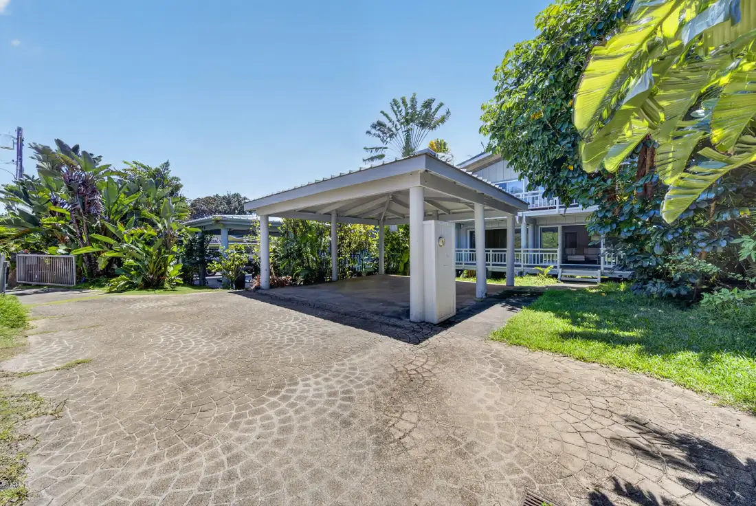 Un patio pavimentado conduce a una entrada cubierta junto a un edificio bajo.