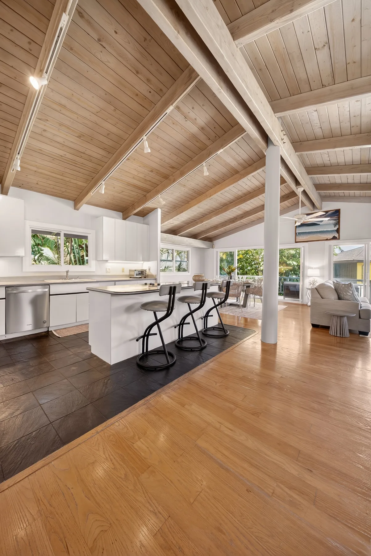 Una luminosa cocina abierta al comedor tiene un techo alto de madera.