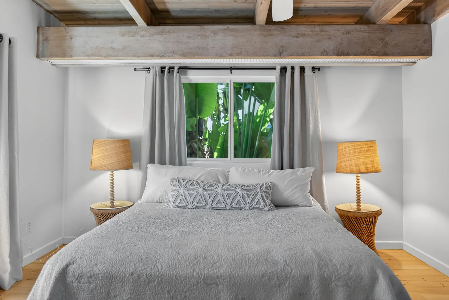 Un dormitorio con una cama bien hecha bajo una ventana.