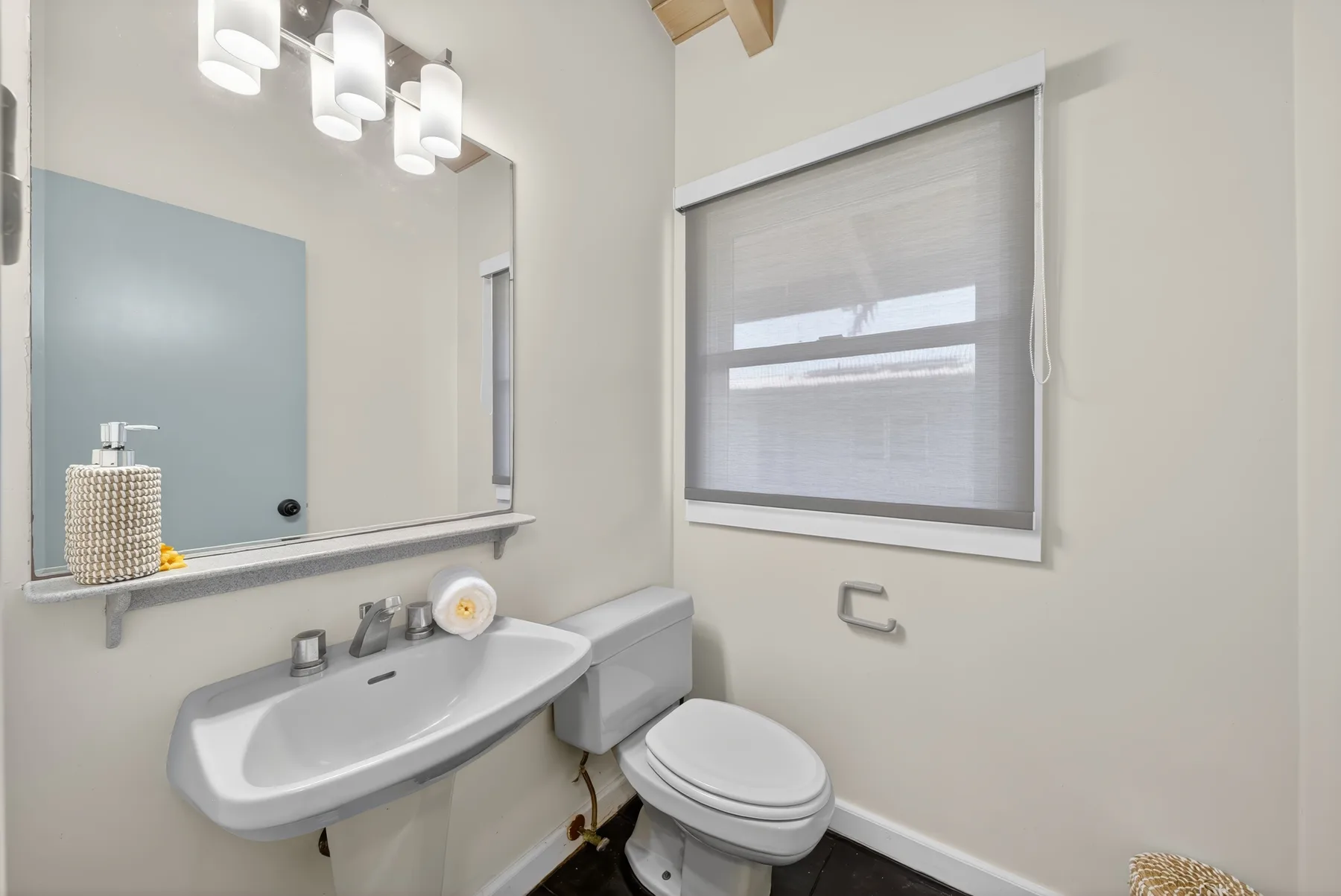 Un baño con lavabo, inodoro y una persiana en la ventana.
