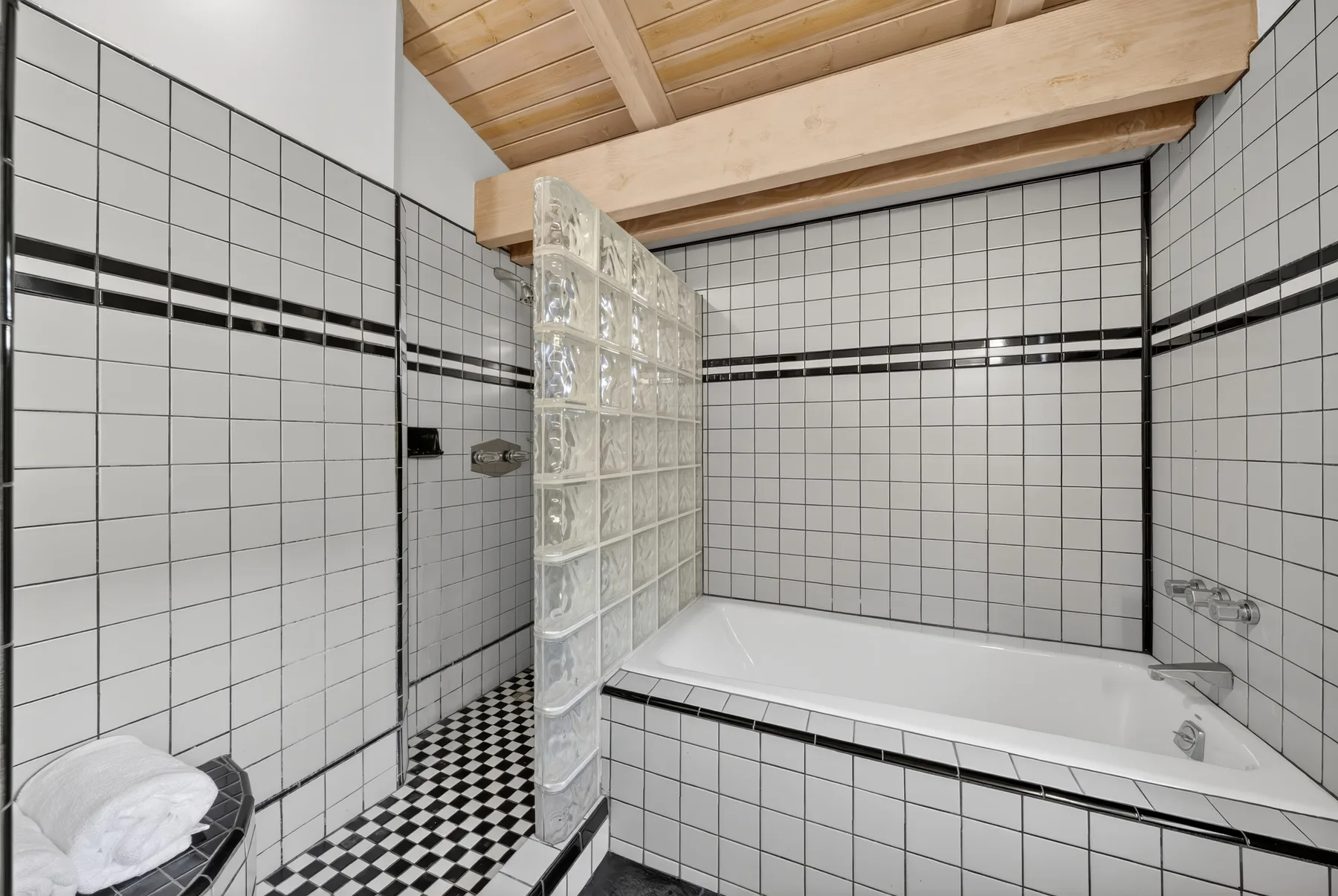 Un baño alicatado con bañera y una pared de bloques de vidrio.