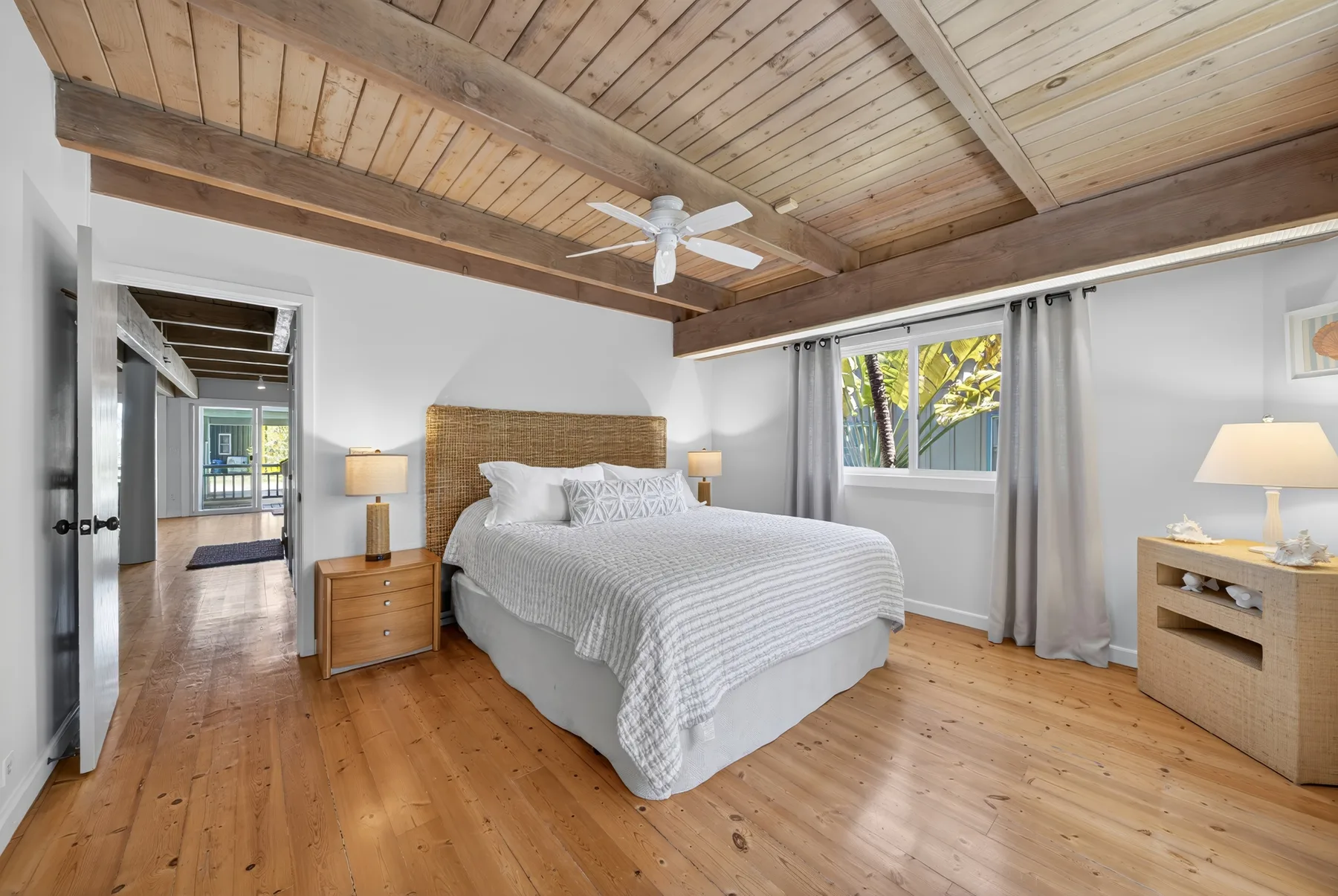 Un dormitorio con una cama, mesitas de noche y un techo de tablones de madera.