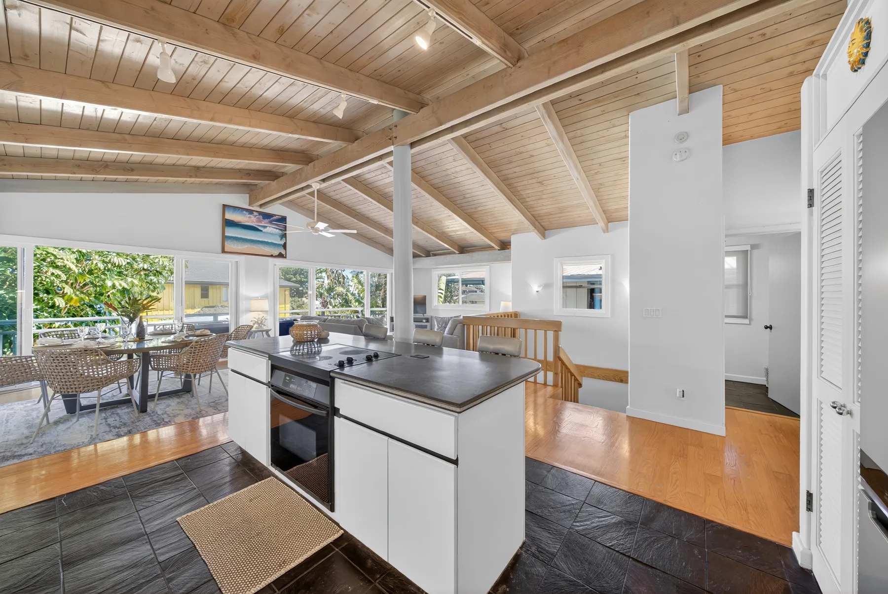 Una cocina abierta con una isla central y un comedor junto a grandes ventanas.