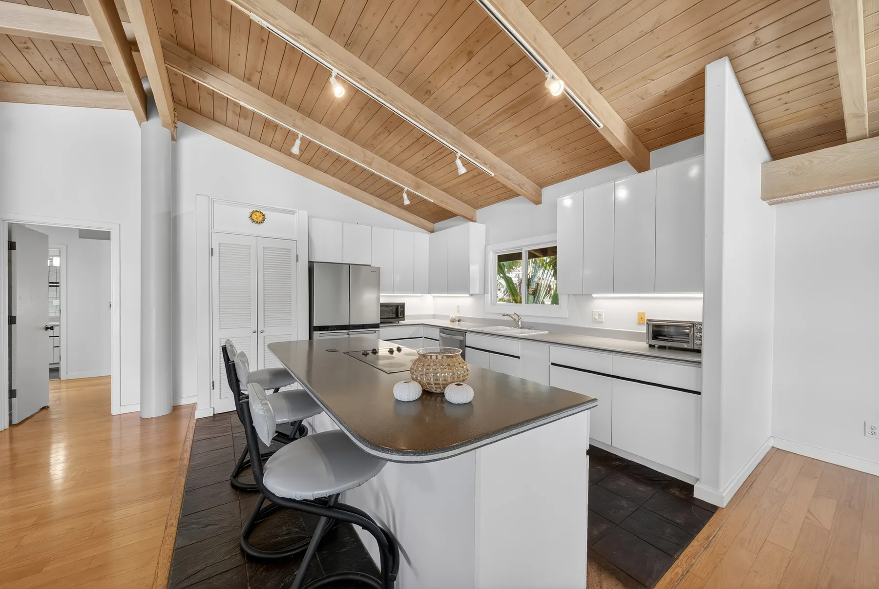 Una cocina luminosa con una isla central y vigas de madera vistas en el techo.