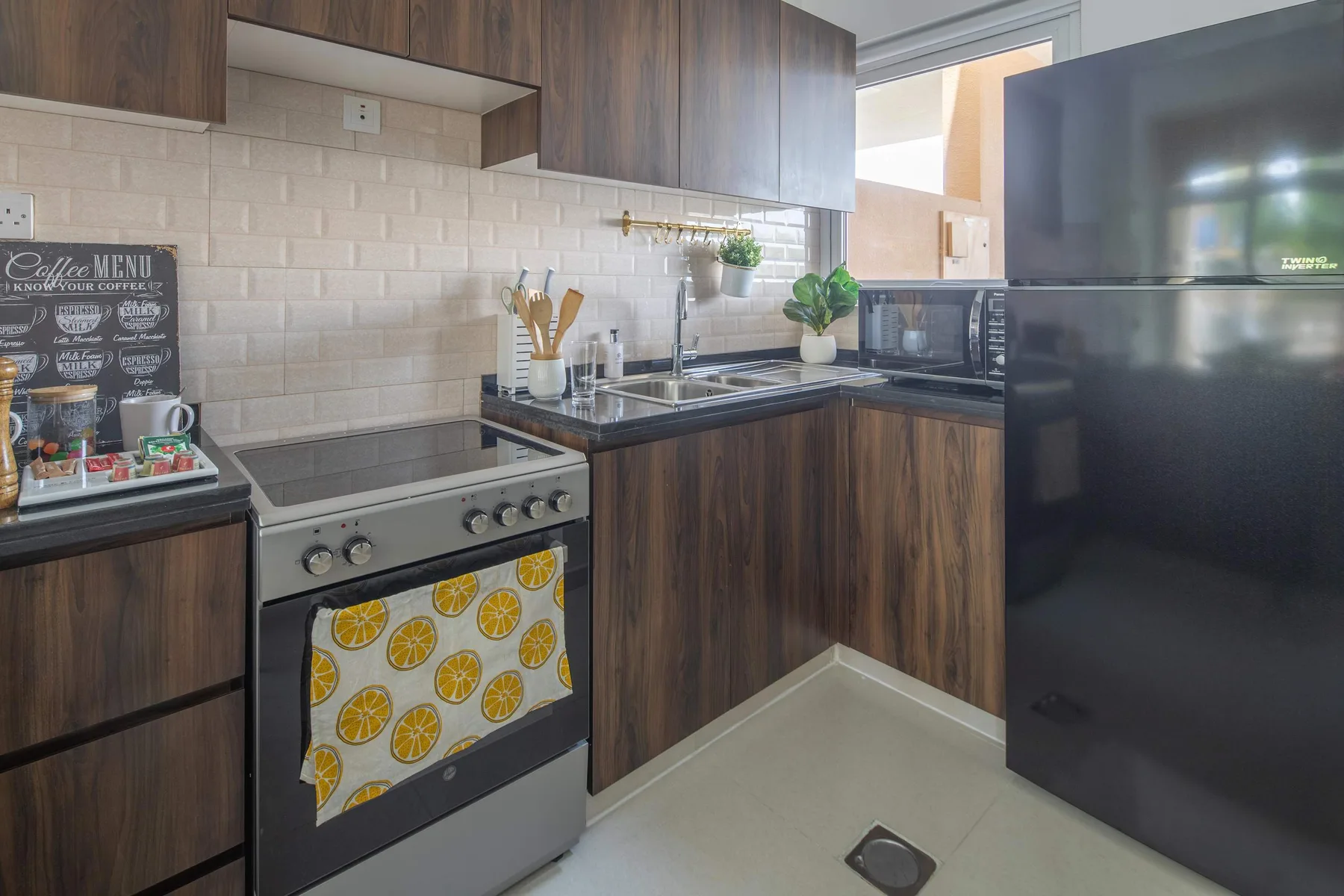 Una cocina con gabinetes de madera oscura, una estufa y un refrigerador negro.