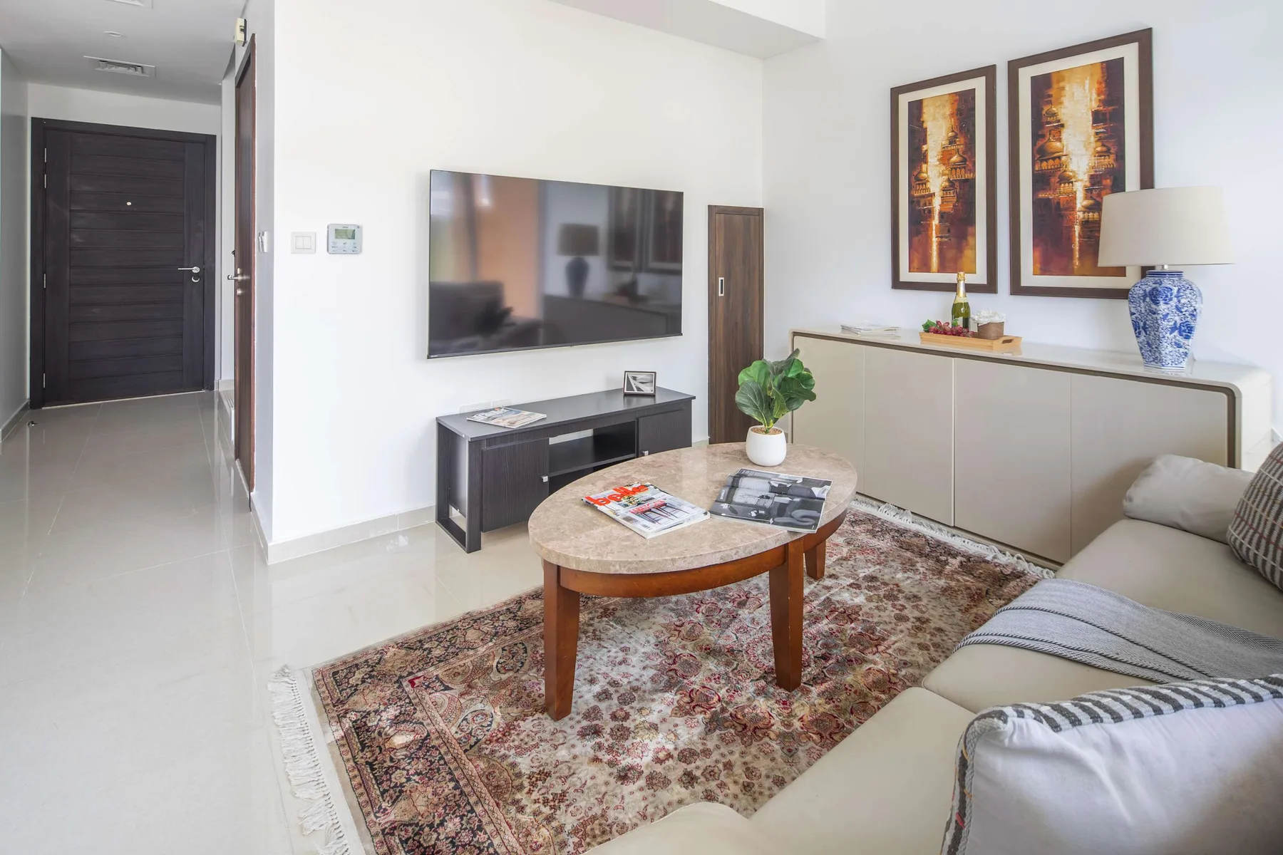 Una sala de estar con televisor, mesa de centro y asientos sobre una alfombra estampada.