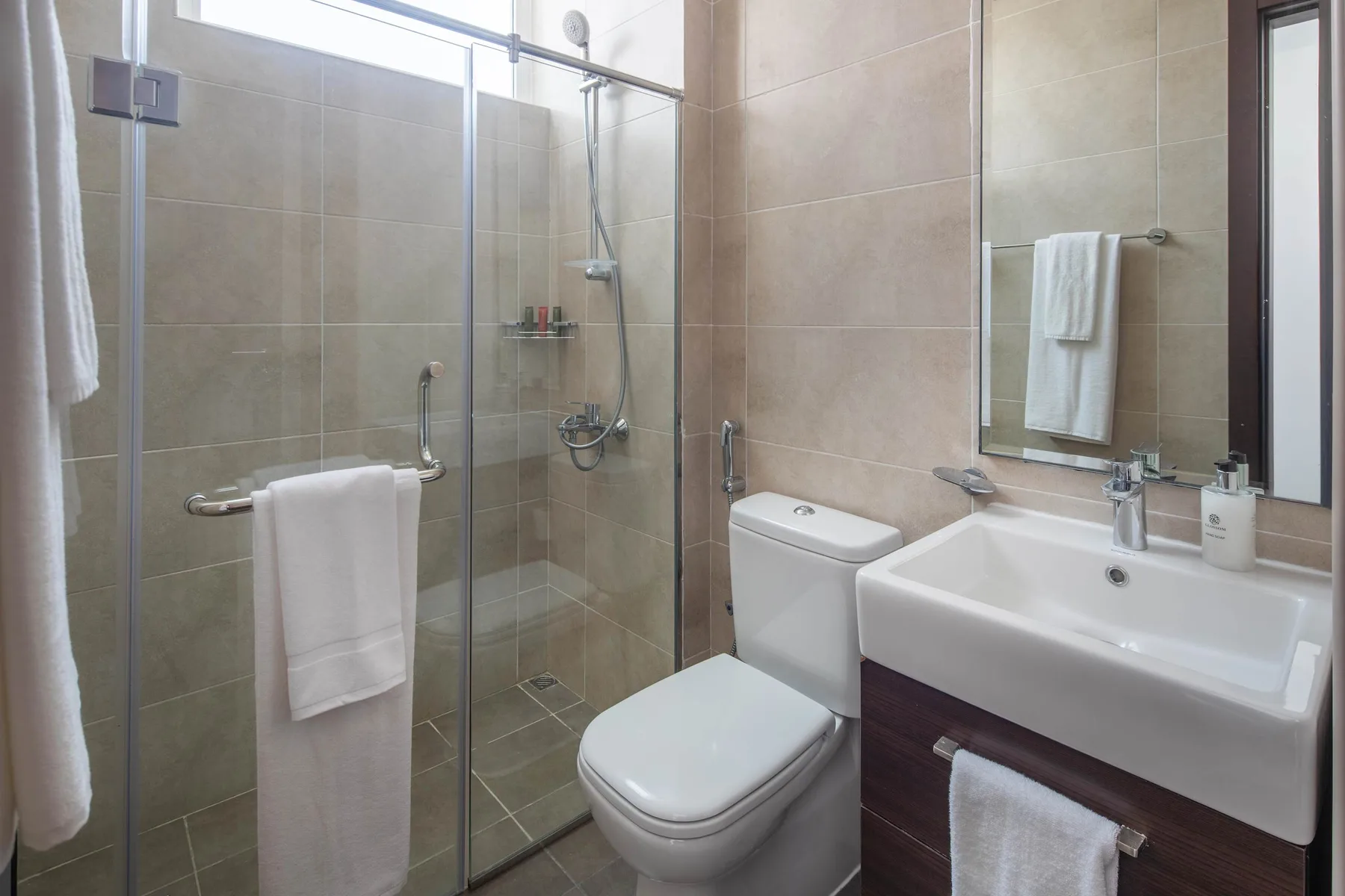 Un baño con ducha de vidrio, inodoro y lavabo.