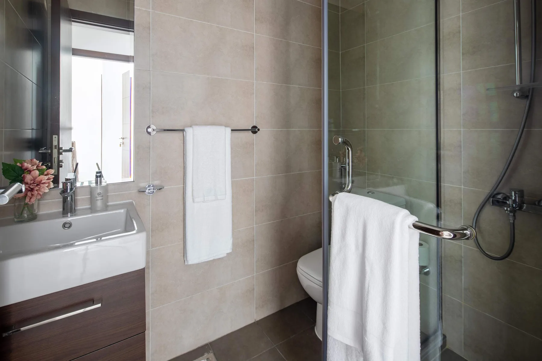 Un baño con azulejos, lavabo, inodoro y ducha de vidrio.