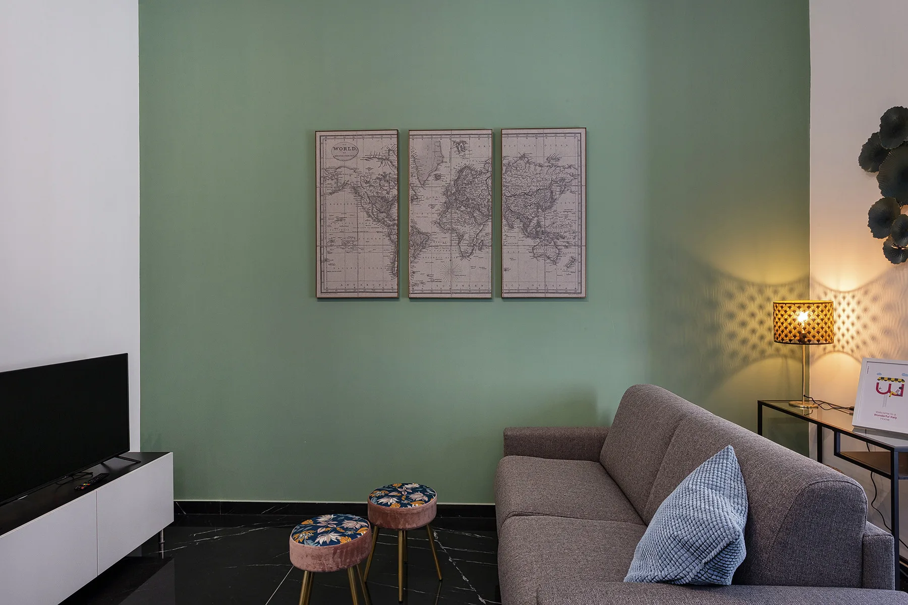 Una sala de estar con asientos grises, cuadros en la pared y un televisor.